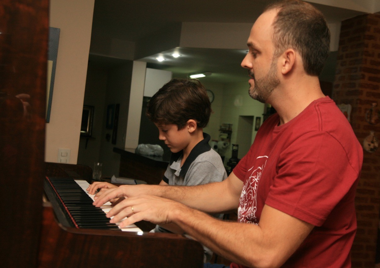 Helcio Baroni tocando piano junto ao seu aluno