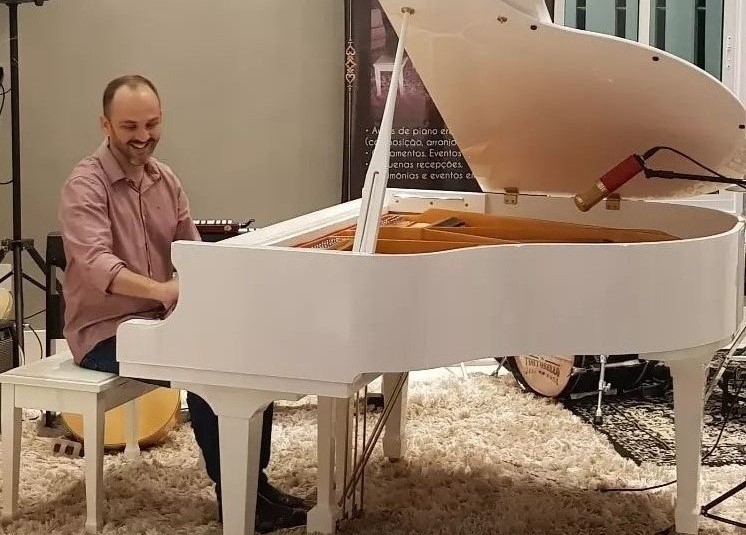 Helcio Baroni tocando piano junto ao seu aluno
