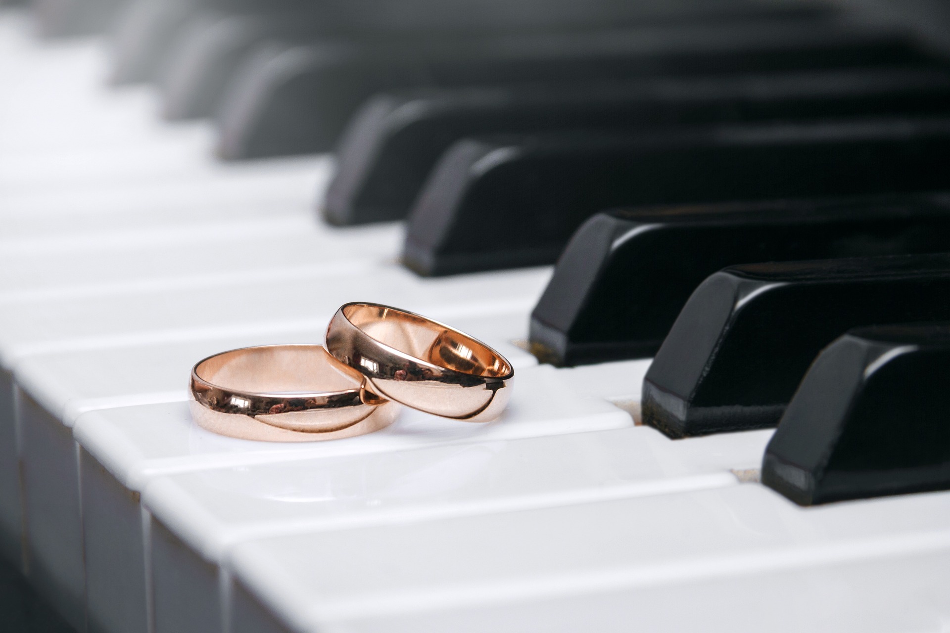 Piano com alianças douradas de casamento em cima das teclas